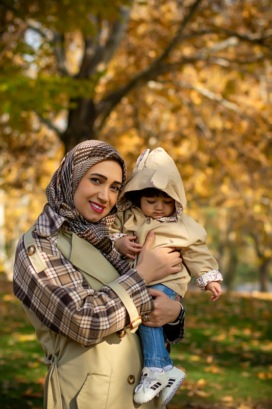 A mother and child pose in an autumn park.