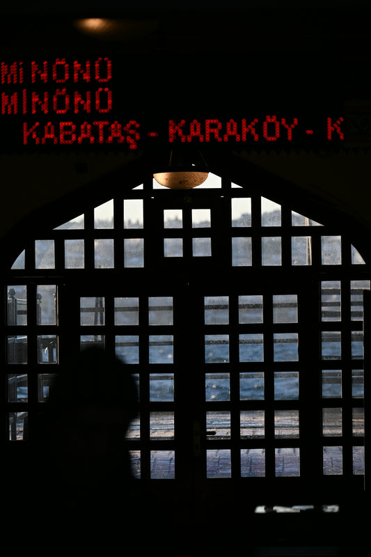 Silhouette of person against arched window with ferry destinations.
