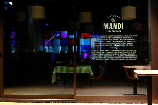 Osteria mandi restaurant exterior at night with colorful interior lights.